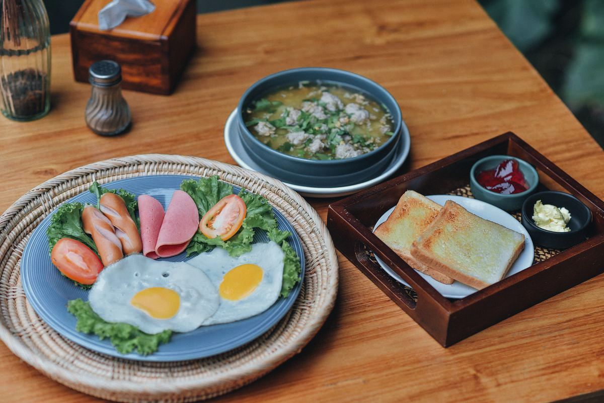 Thai rice porridge, toast and coffee on a rattan tray