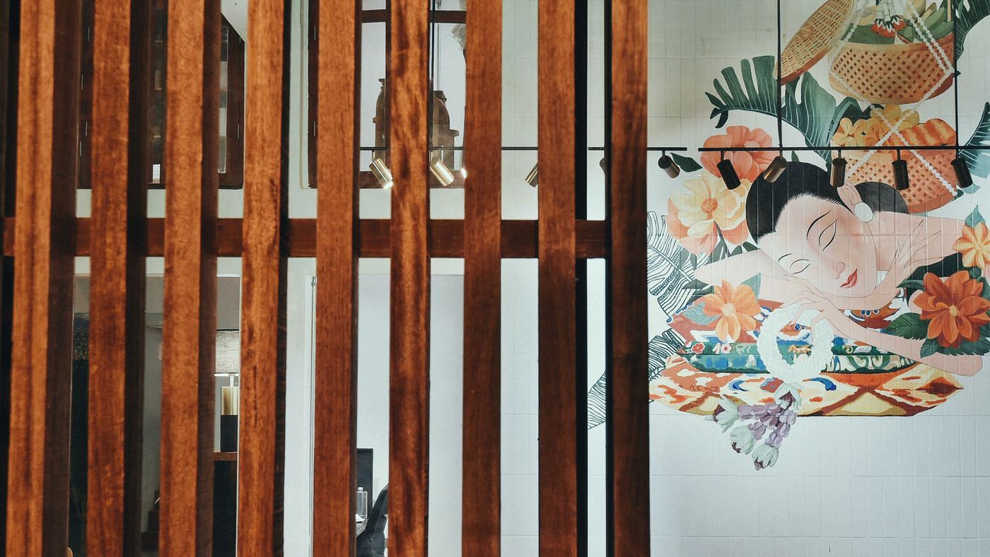 Mural of a woman among flowers behind teak slats