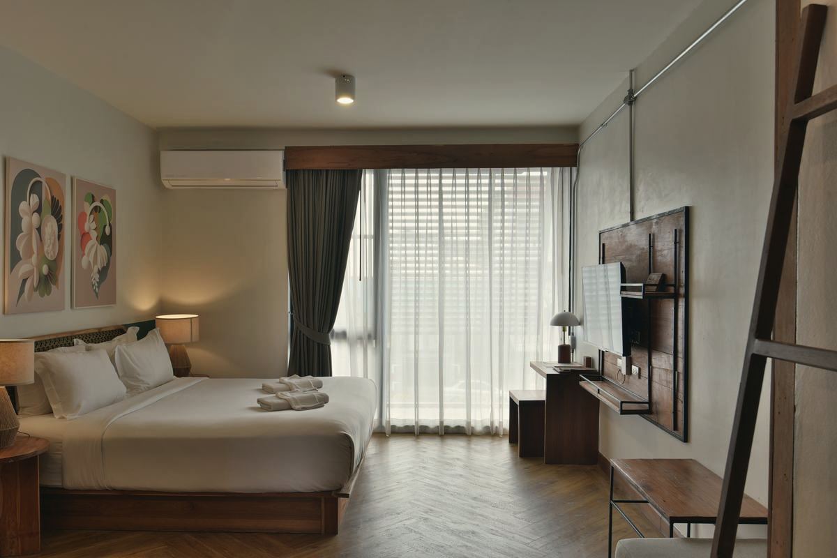 Holy Deluxe king bed with artwork, teak TV wall and a bright window