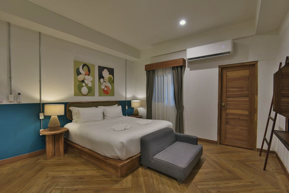 Holy Deluxe Plus with king bed, artwork and sofa at the foot of the bed