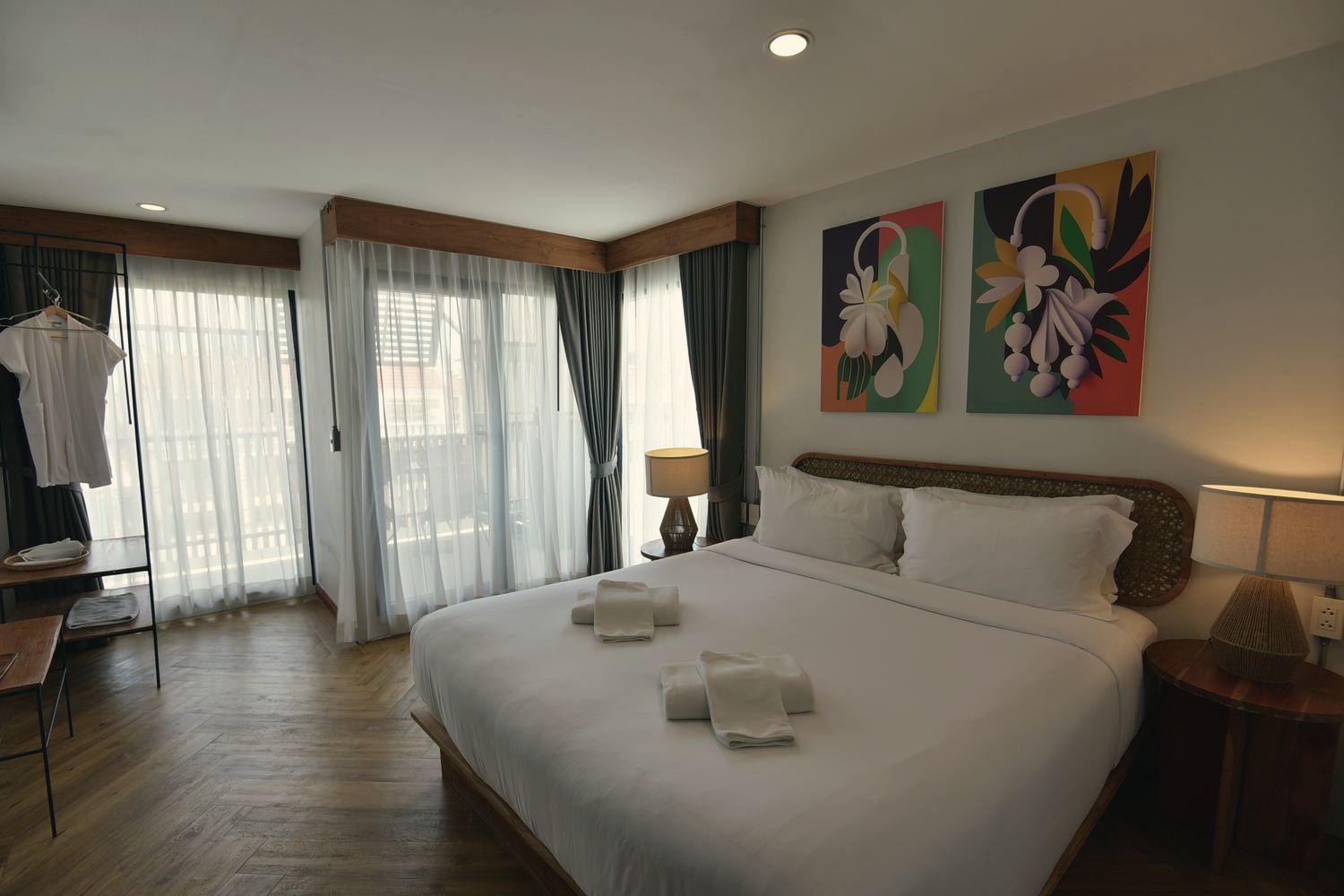 KWANS Suite bedroom with king bed, artwork and tall windows