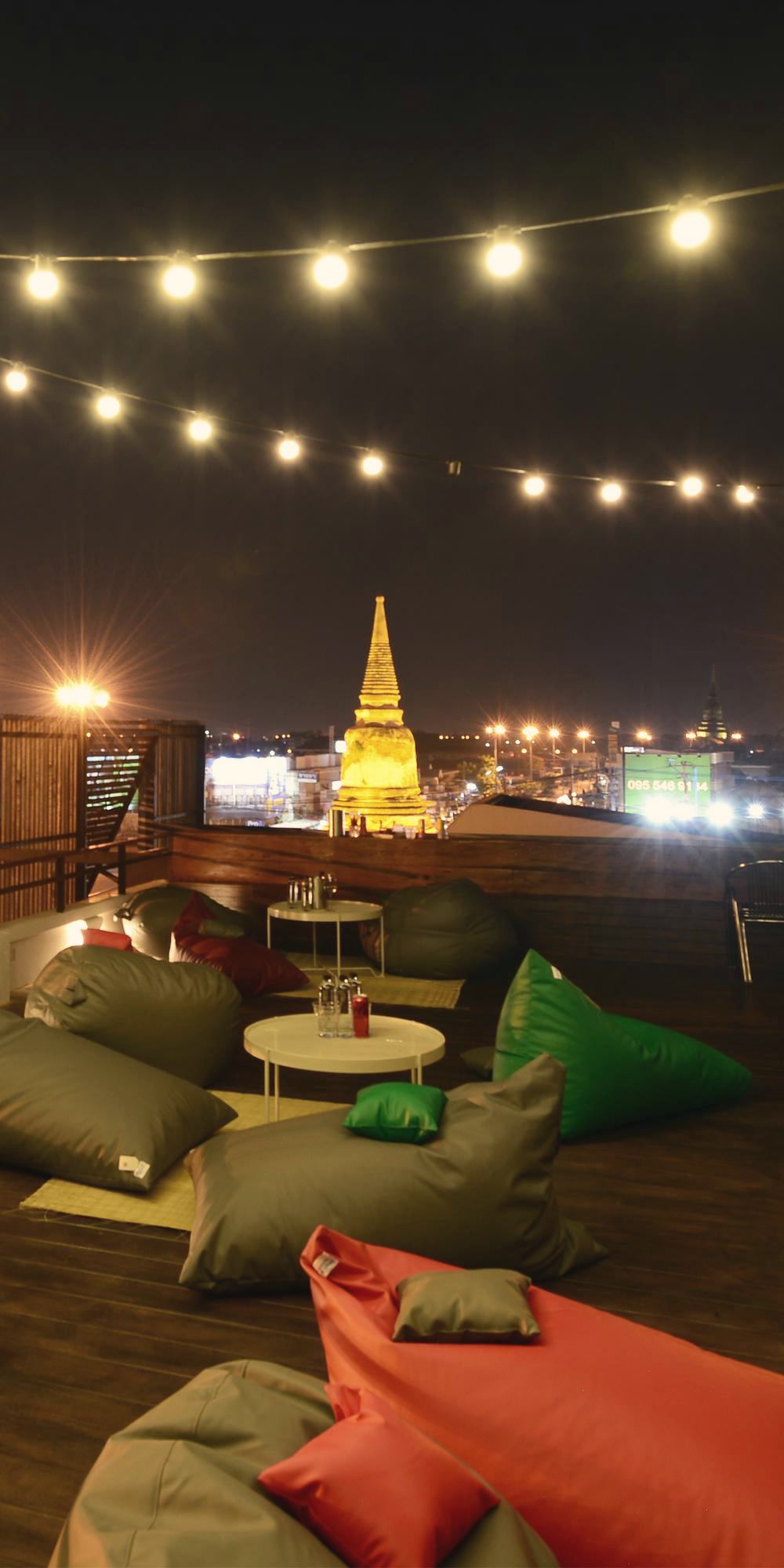 Rooftop beanbags under string lights with an illuminated chedi